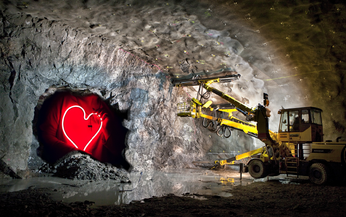 En maskin står framför en tunnelöppning i berget. Inne i tunneln syns ett rött hjärta (kollage).