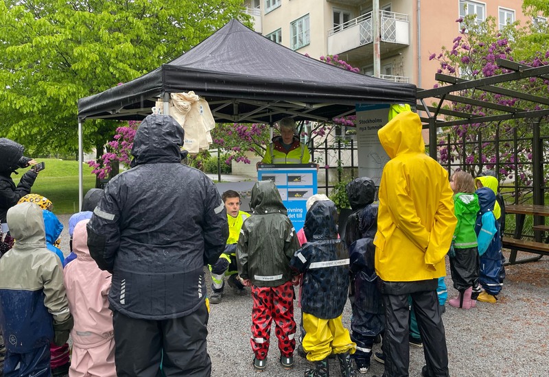Medarbetare från Region Stockholm berättar om nya tunnelbanan för förskolebarn i regnkläder. 