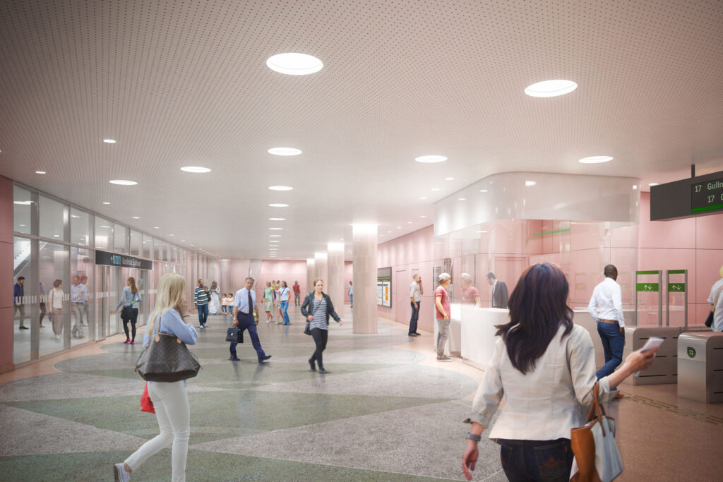 Visionsbild av den kommande Hagastaden tunnelbanestation, där människor rör sig genom en ljus och rymlig hall med rosa väggar och en modern biljettlucka.