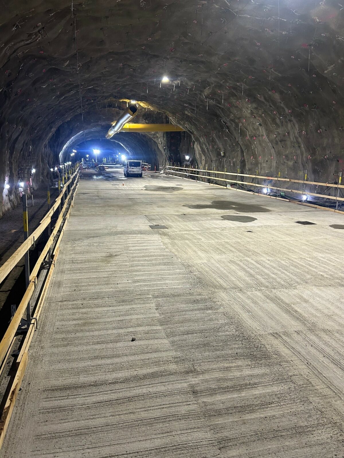 Bilden visar en stor golvyta i betong i en bergtunnel. På vardera sidan finns ett staket av trä.