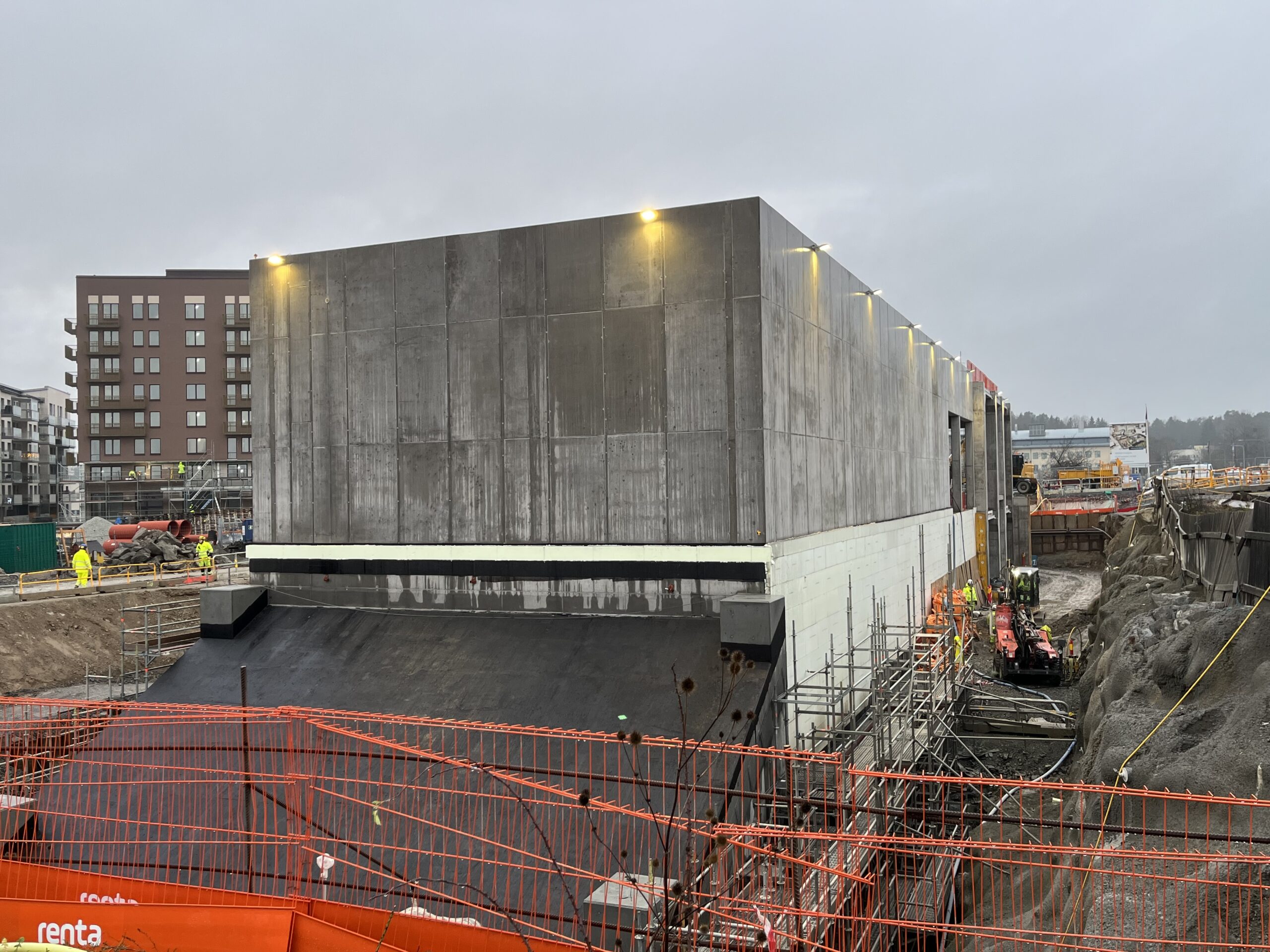 Byggarbetsplats med stor betongbyggnad.