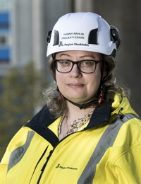 En kvinna iförd skyddshjälm och gul jacka.
