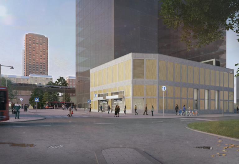 En gul stationsbyggnad framför ett grått höghus.