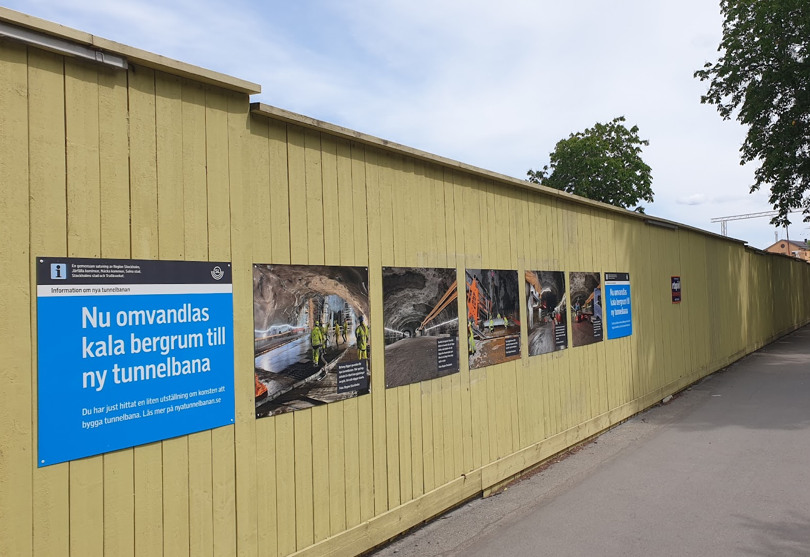 Det gula byggplanket har skyltar med fotografier som visar arbetet under jord.