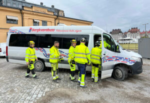 Människor i gula arbetskläder går in i en buss.