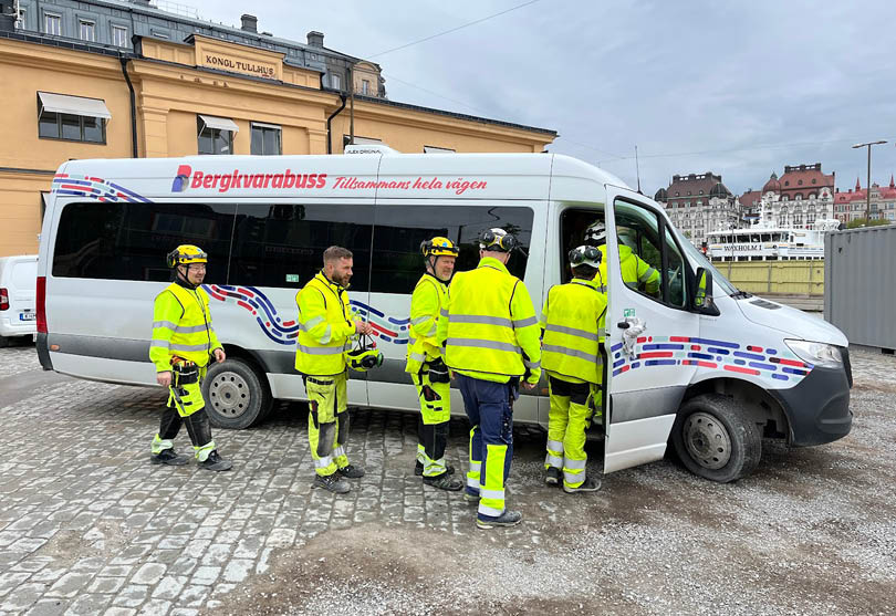 Människor i gula arbetskläder går in i en buss.