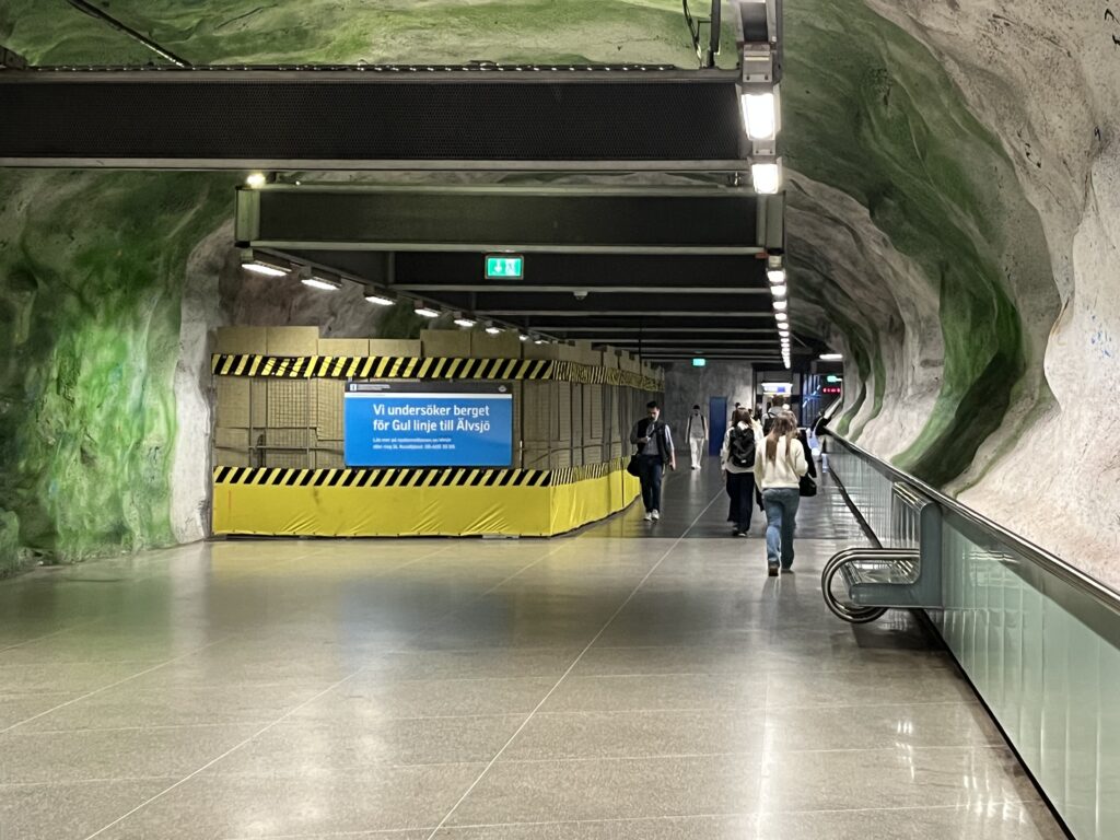 människor går i tunnel, bredvid en inhägnad arbetsplats.