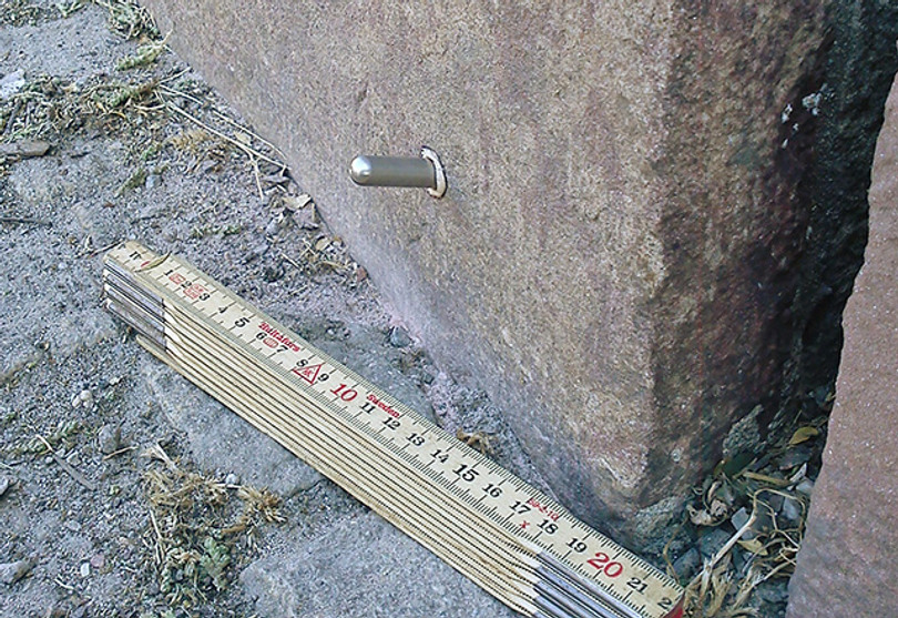 En pigg sticker ut ur en mur. En tumstock ligger bredvid.