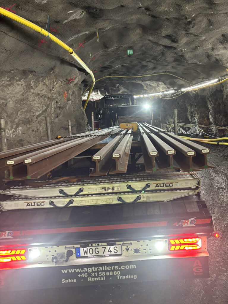 En lastbil lastad med räler som kör i en tunnel.