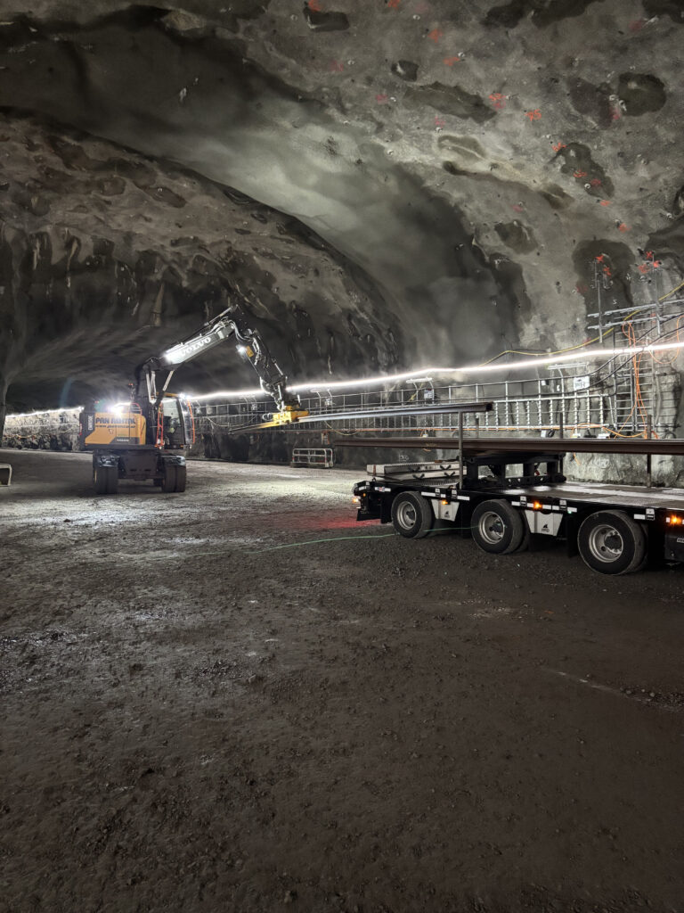 En maskin lastar av ny räls från en lastbil.