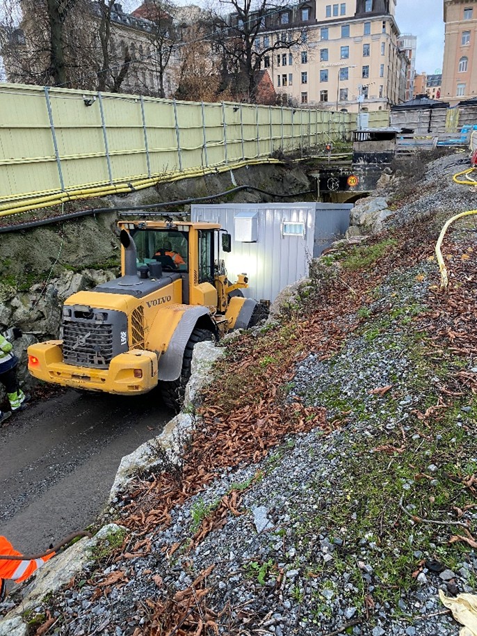 Hjullastare kör ner ett grått containerliknande föremål i en tunnel.