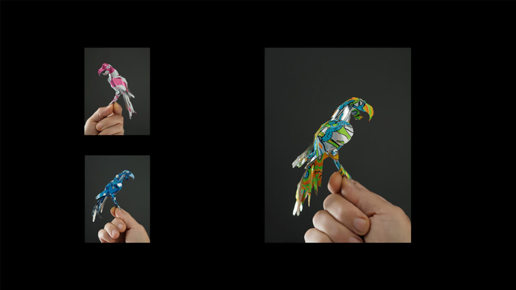 En hand som håller tre origamifåglar i olika fäger.